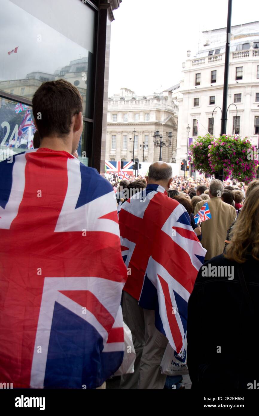 Due uomini visti dalla parte posteriore drappeggiato in bandiere dell'Unione, Unions jacks a Londra , Inghilterra Foto Stock