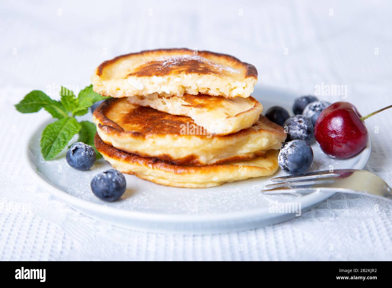Frittelle di formaggio cottage (syrniki). Cheesecake fatti in casa da formaggio cottage con frutti di bosco. Piatto tradizionale russo. Primo piano. Foto Stock
