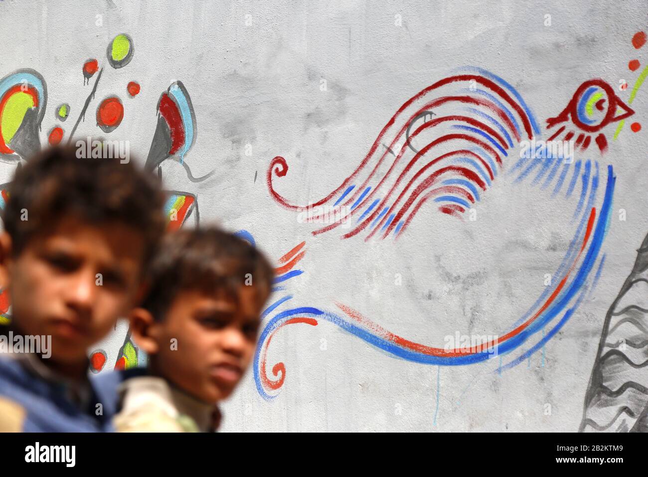 Sanaa, Yemen. 3rd Mar, 2020. I bambini camminano per graffiti in una strada a Sanaa, Yemen, 3 marzo 2020. Gli attivisti yemeniti a Sanaa hanno tenuto martedì una campagna di disegno dei graffiti che chiede la pace e fa appello a tutti i partiti di guerra dello Yemen per sedersi sul tavolo negoziale e lavorare insieme per porre fine alla guerra in corso. Credit: Maometto/Xinhua/Alamy Live News Foto Stock