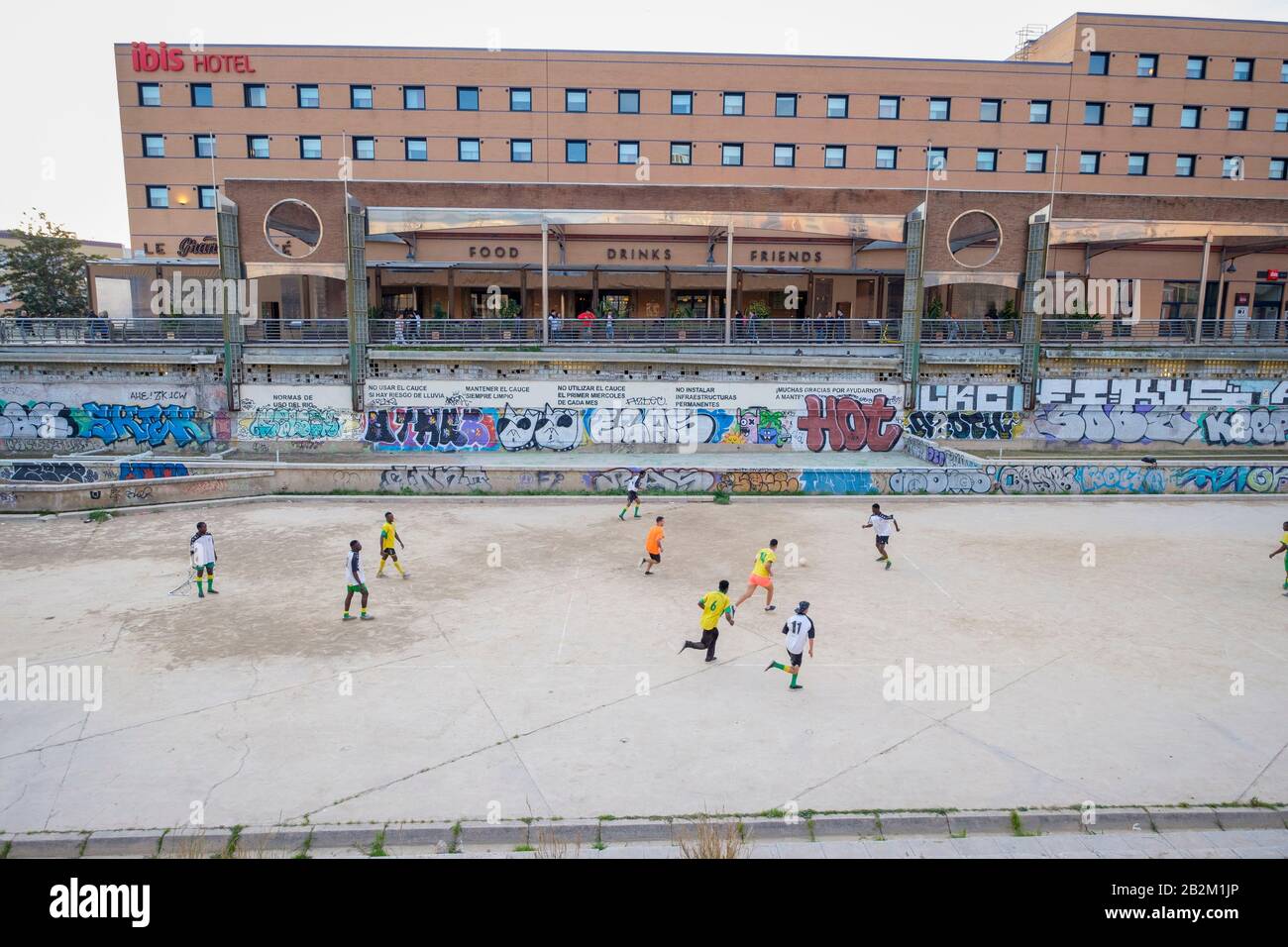 Persone che pagano il calcio nel fiume essiccato Rio Guadaimedina. Foto Stock