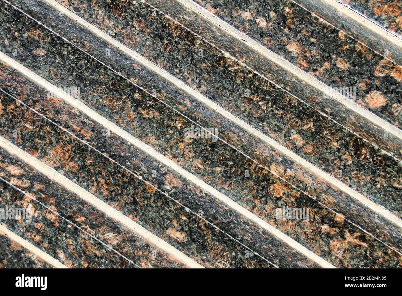 Una vista ravvicinata astratta di file diagonali di granito nero e oro. Foto Stock