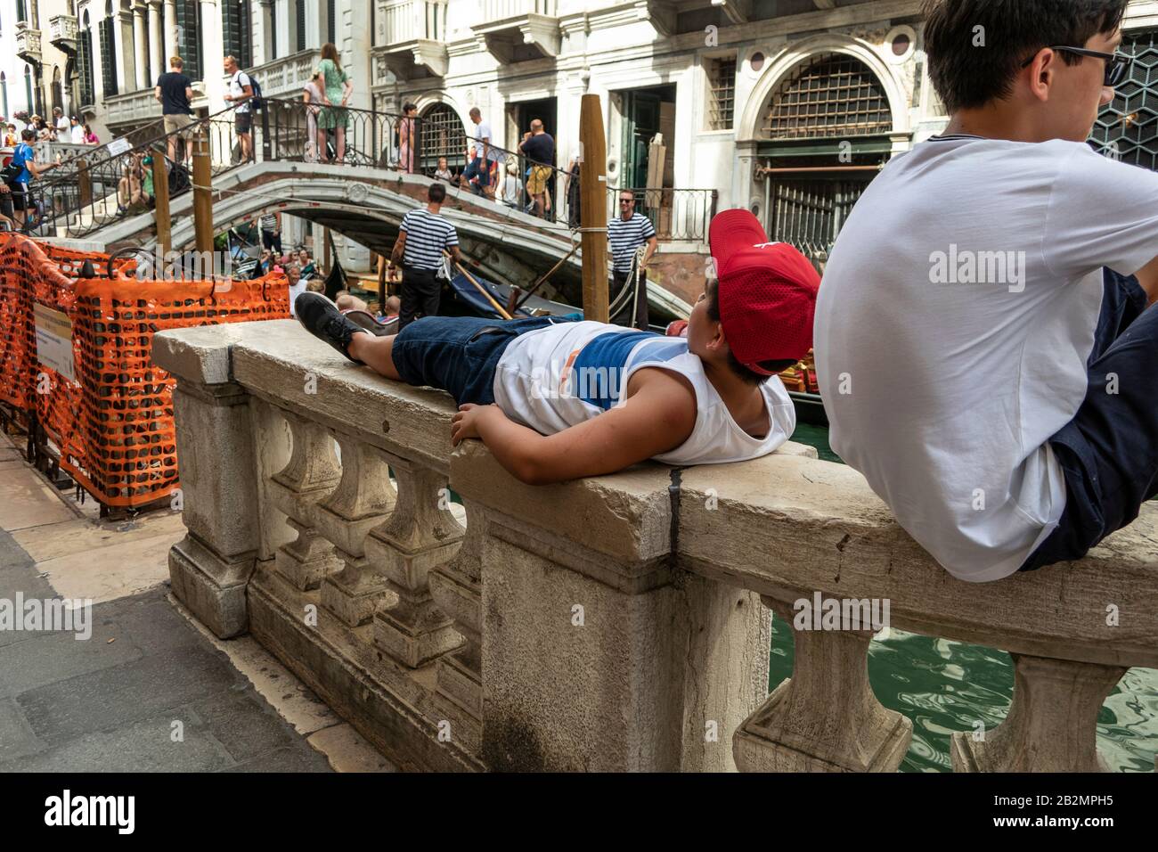 Ragazzo che si posa sul muro del canale, riposante, Venezia, Italia Foto Stock