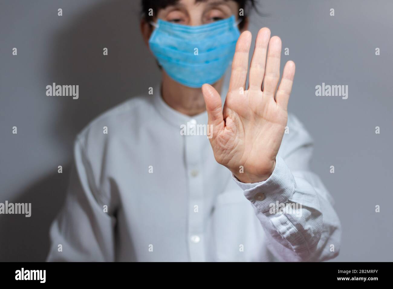 Arrestare la quarantena del coronavirus e il concetto di inquinamento atmosferico pm2.5. Donna anziana malata che indossa maschera respiratore per proteggere con braccio allungato. Wuhan, Cina ep Foto Stock