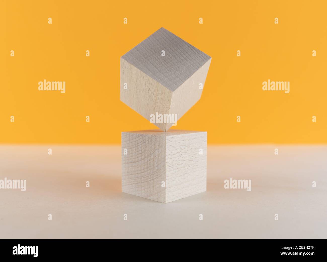 cubo di legno in piedi equilibrato su un angolo in cima ad un altro, concetto di rischio e di equilibrio Foto Stock