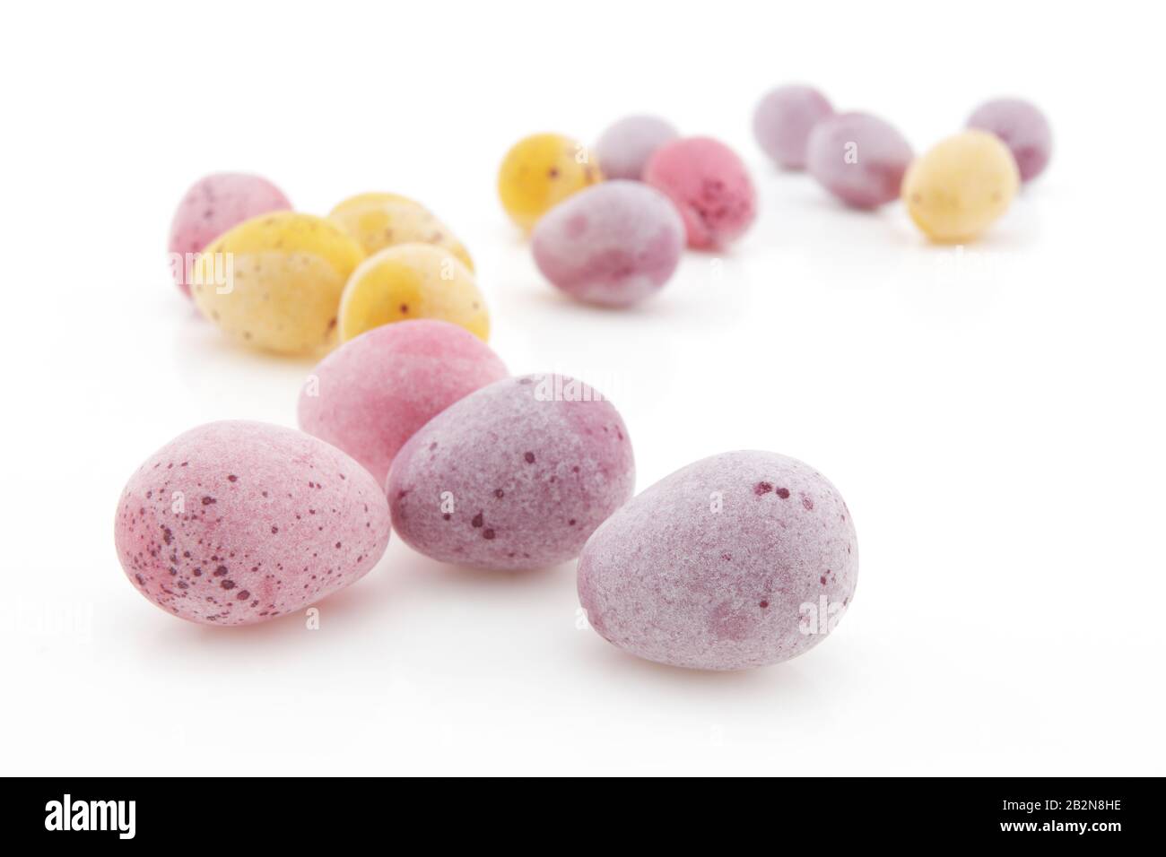 Un gruppo di piccole uova di Pasqua su bianco con fuoco selettivo e profondità di campo poco profonda Foto Stock