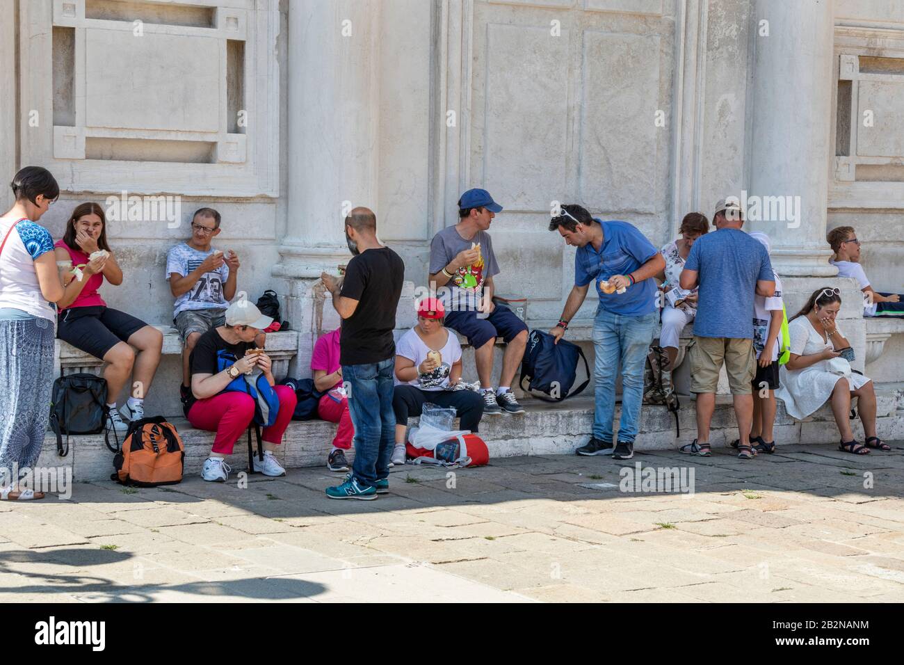 Turisti che mangiano e si siedono su gradini di un edificio, Venezia, italia. Nuove leggi a Venezia Italia contro i turisti che si comportano male. Foto Stock