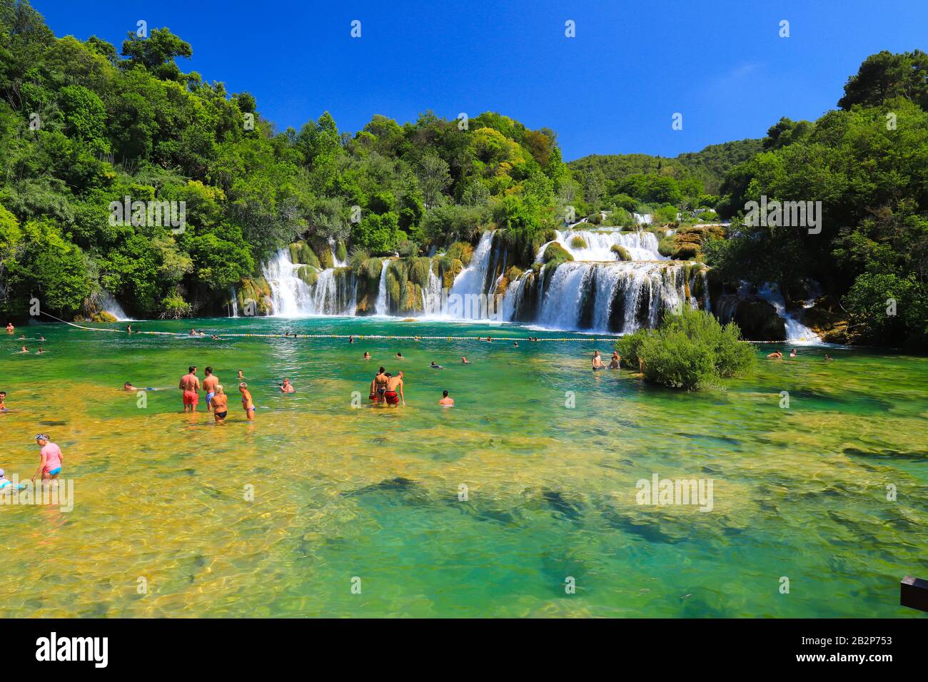 I turisti nuotano nel lago vicino alla pittoresca cascata in estate. Le più belle e belle cascate croate, montagne e natura. Krka Nationa Foto Stock