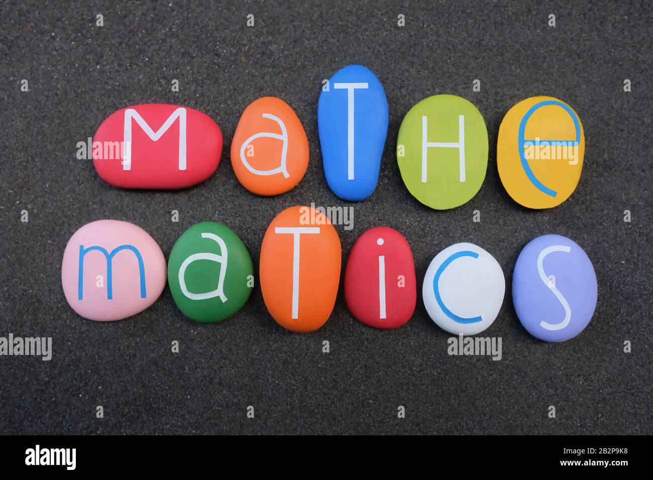Testo matematico composto da lettere di pietra multicolore, scienza, tecnologia, ingegneria, concetto di educazione matematica su sabbia vulcanica nera Foto Stock