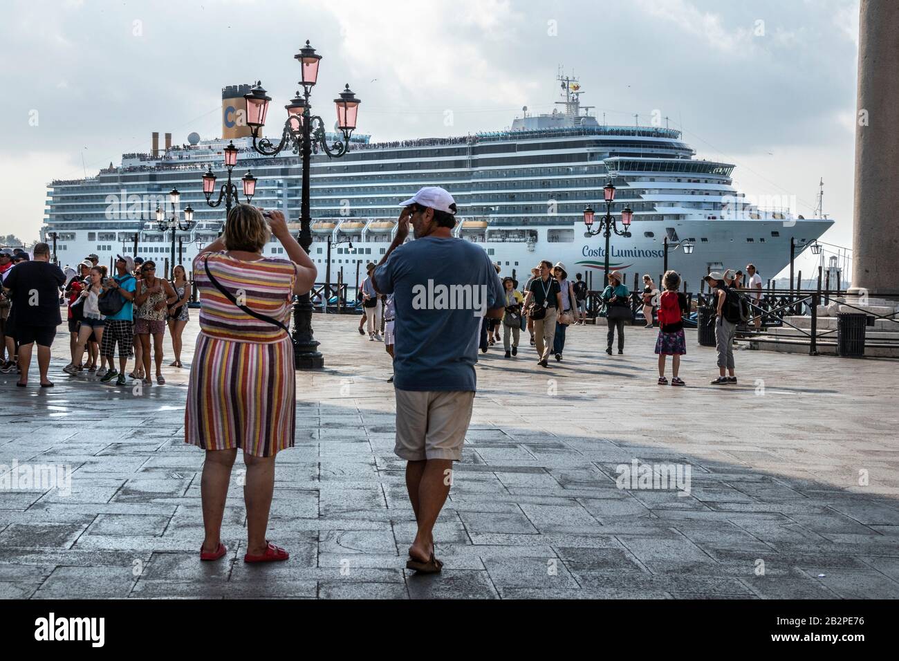 I turisti che scattano foto dell'arrivo quotidiano delle navi da crociera di prima mattina in Piazza San Marco, Venezia, Italia Foto Stock