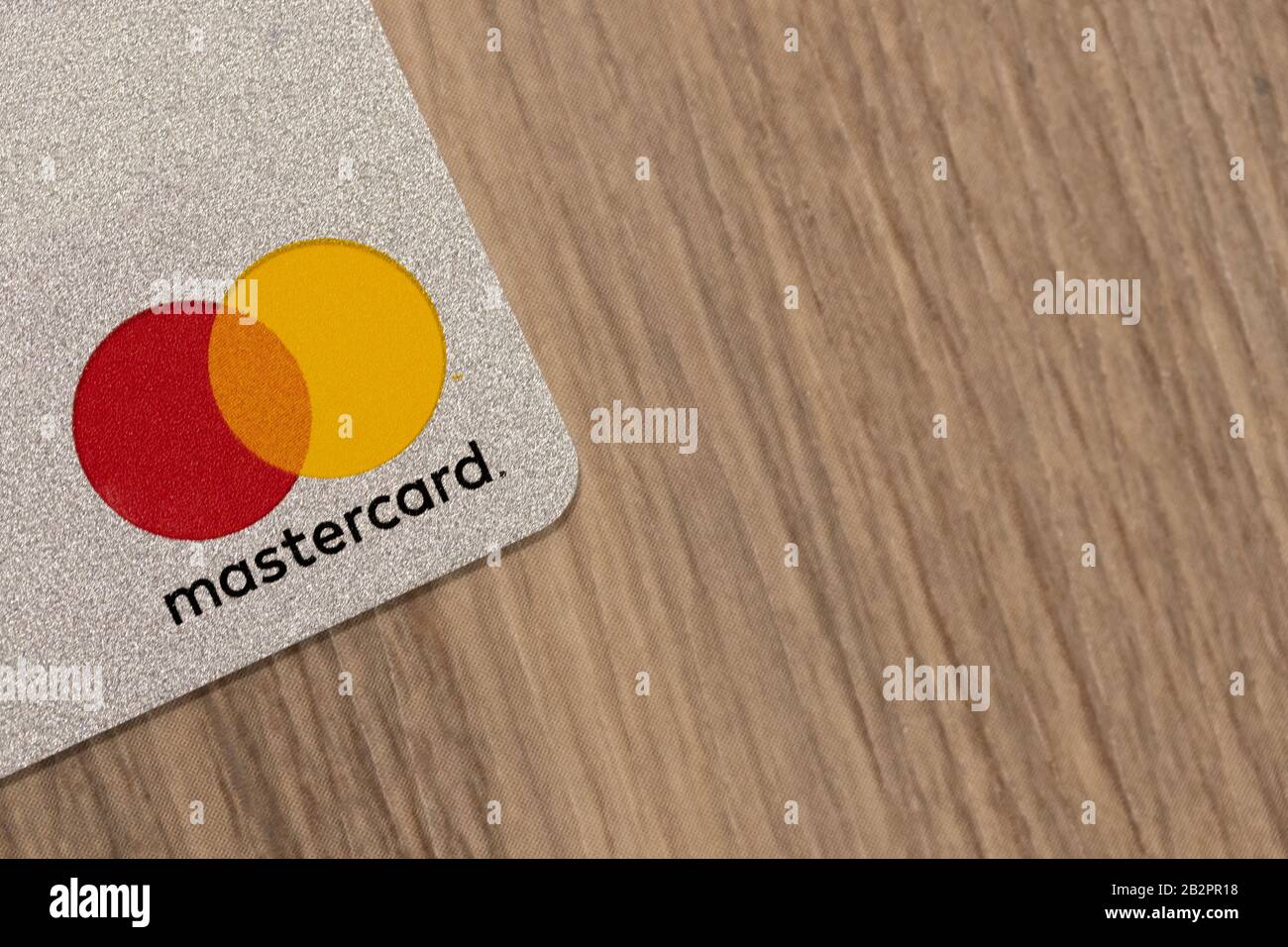 Il logo Mastercard su una carta di credito argentata mentre è collocato su un tavolo. Foto Stock