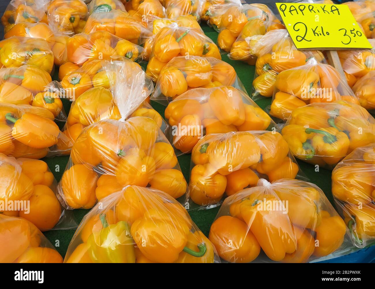 Molti peperoni gialli (parola tedesca sul segno: Paprika) in sacchetti di plastica sul mercato olandese Foto Stock