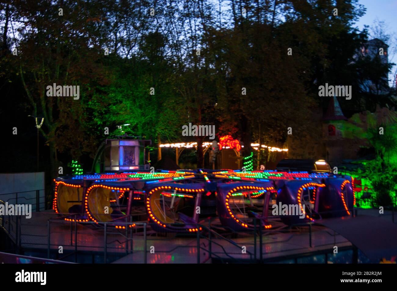 Carousel in luci luminose su un buio estate sud notte contro uno sfondo di alberi e altre attrazioni. Parco, attività, riposo Foto Stock