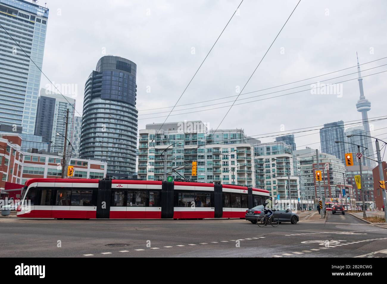 Un Bombardier TTC streetcar è visto su una strada trafficata della città con lo skyline del centro città, CN Tower sullo sfondo. Foto Stock