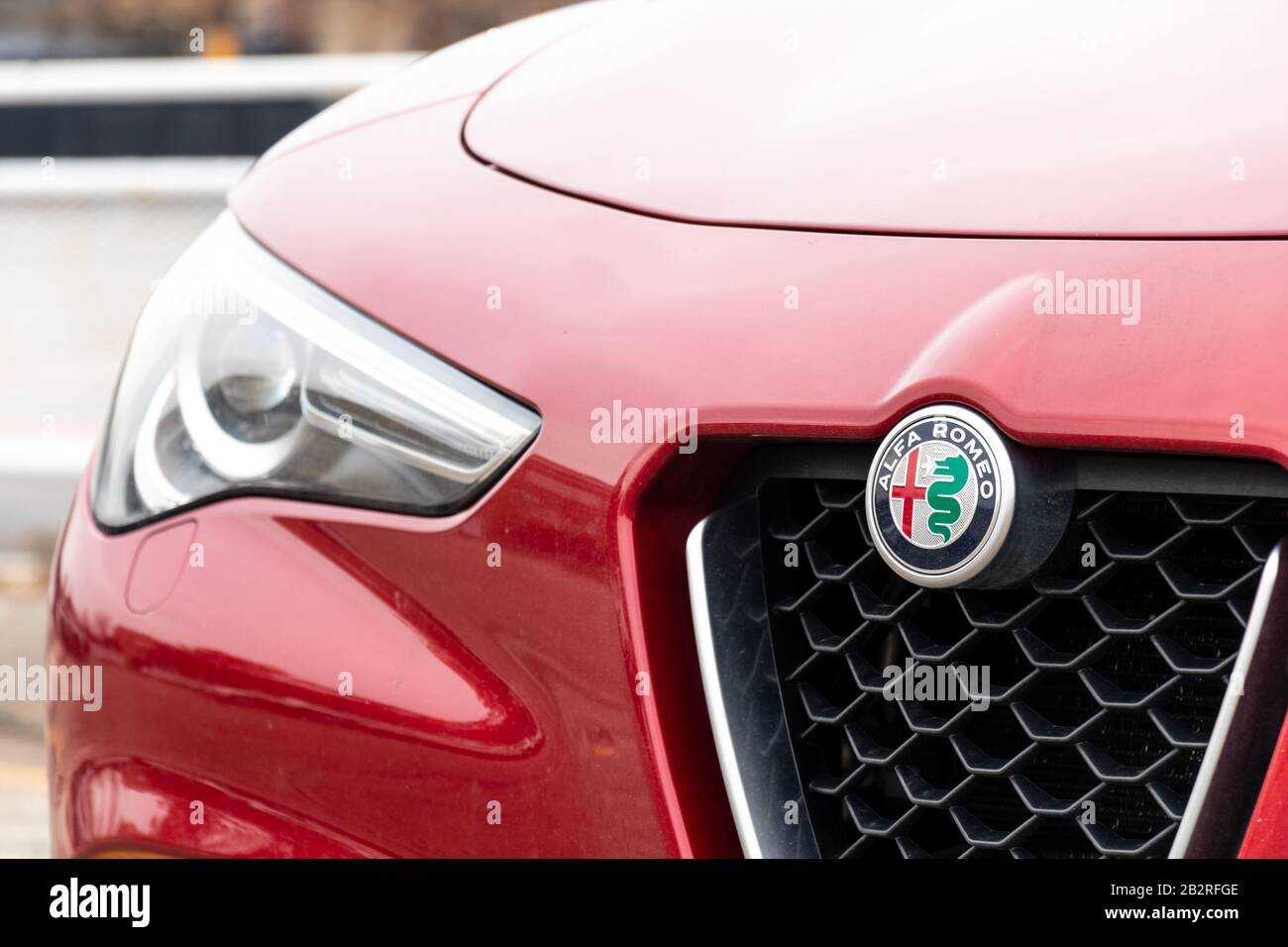 Alfa Romeo emblema sulla parte anteriore di un SUV rosso Stelvio in giornata intensa. Foto Stock