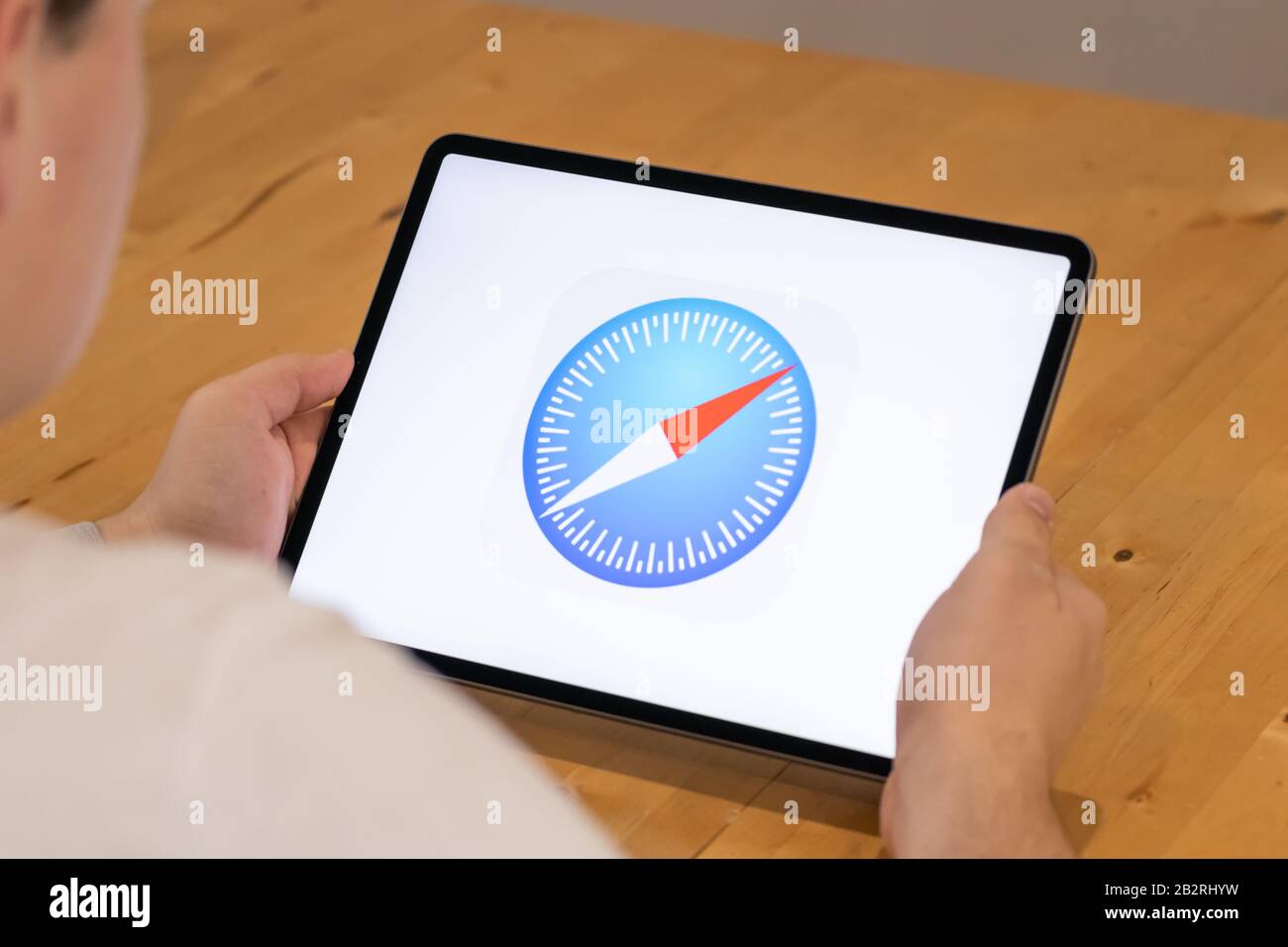 Uomo seduto su una scrivania con un iPad Pro con l'icona del browser Safari sullo schermo. Foto Stock