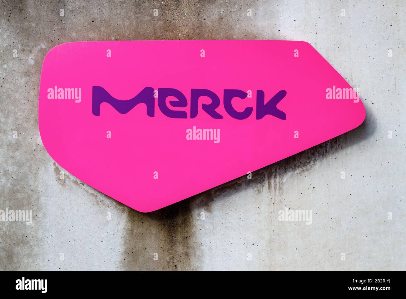 Parete in cemento con logo Merk rosa e viola. Merck è una multinazionale tedesca e farmaceutica. Darmstadt, Germania. Foto Stock