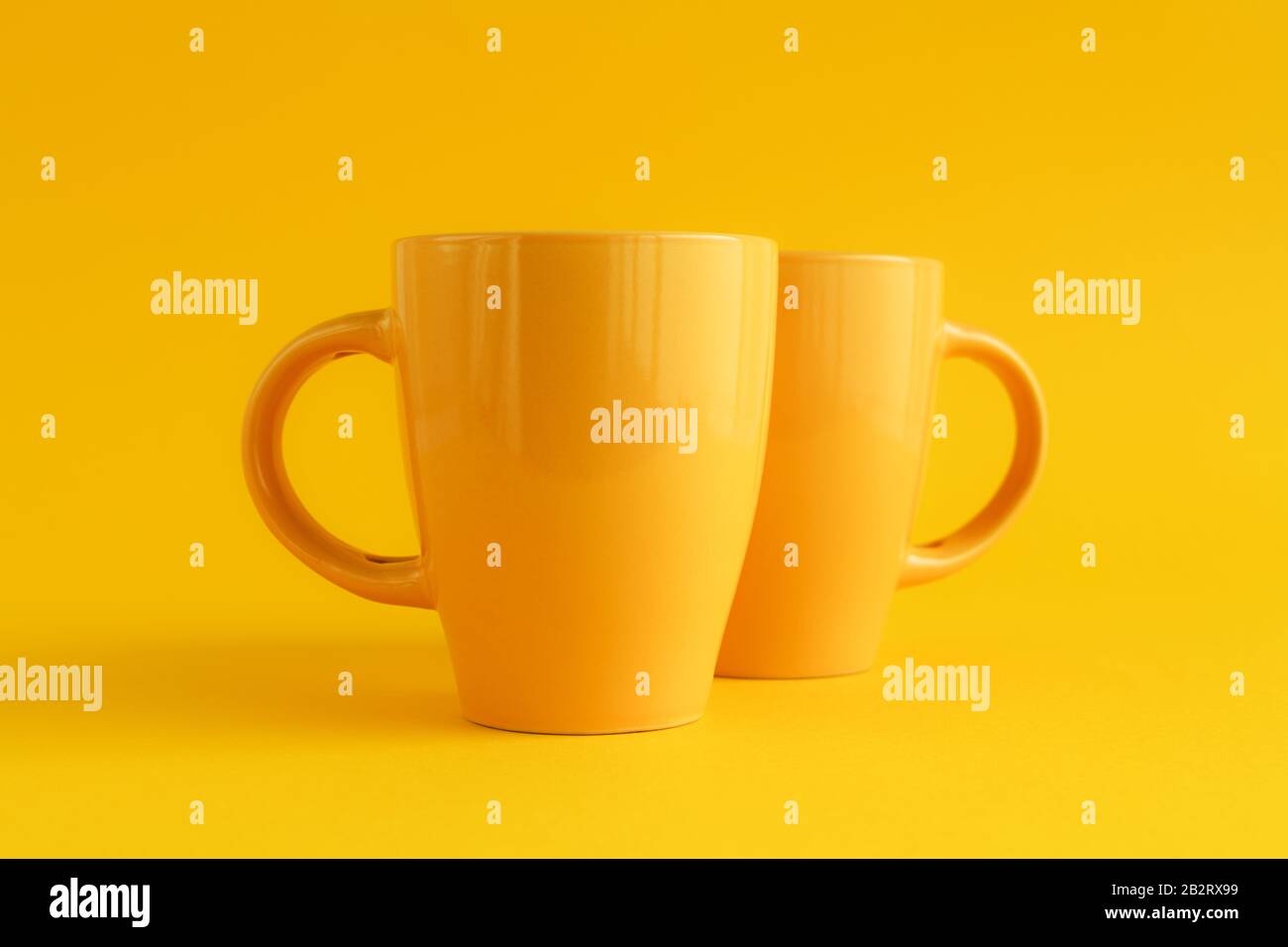 Due tazze di caffè giallo su sfondo giallo, pausa caffè e concetto di dipendenza dalla caffeina Foto Stock
