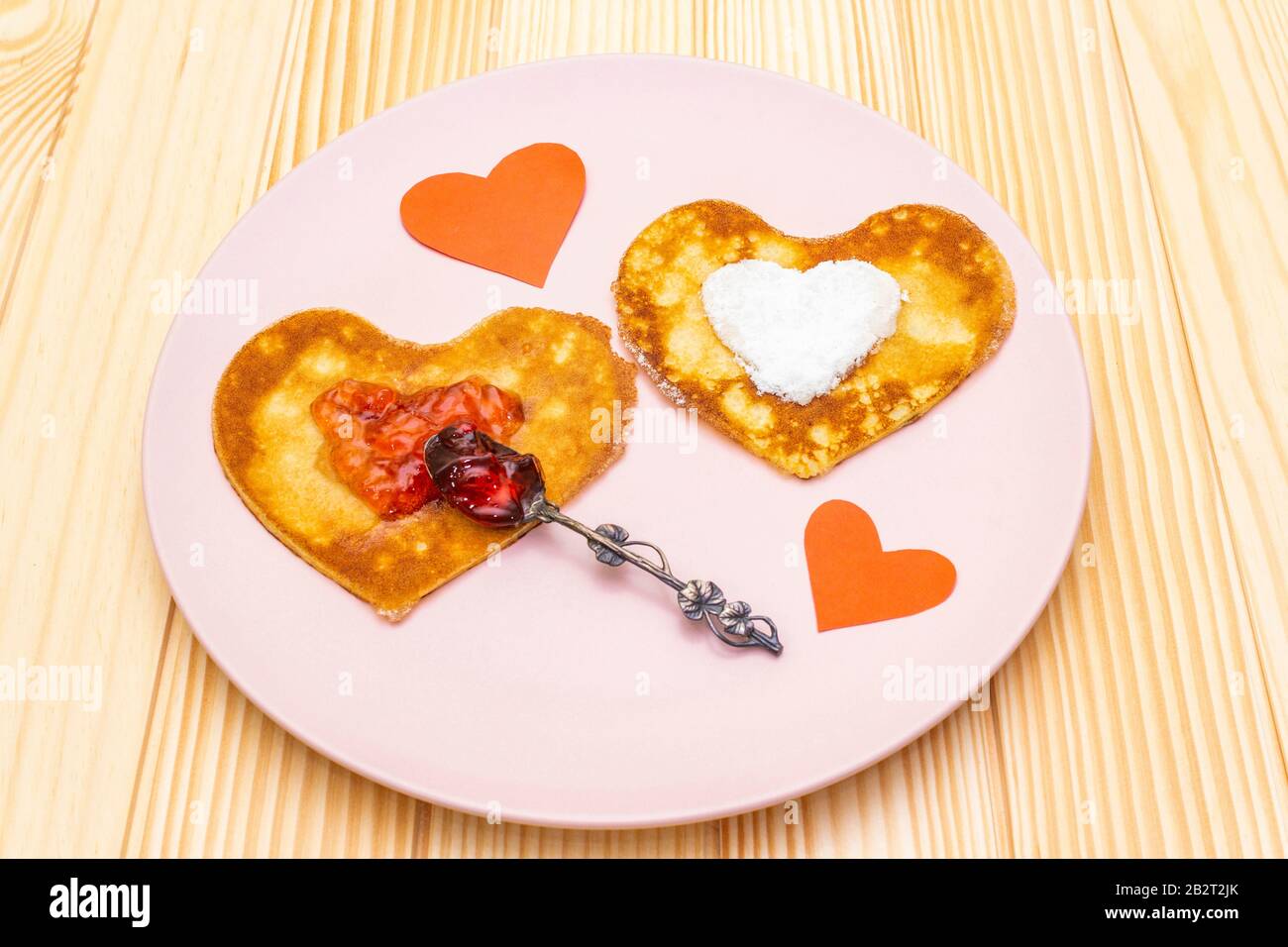 Pancake a forma di cuore per una colazione romantica con marmellata di  fragole, cucchiaio d'argento e cuori di carta. Shrovetide (carnevale)  concetto. Su sfondo di legno Foto stock - Alamy