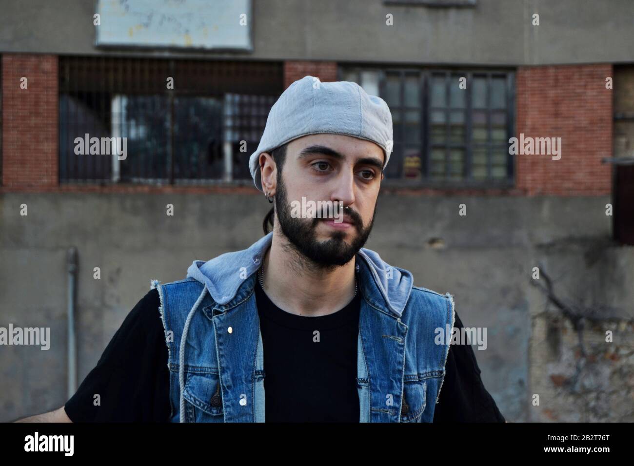 Un uomo triste che indossa berretto e guarda in basso/ un uomo che sale di fronte a un vecchio edificio Foto Stock