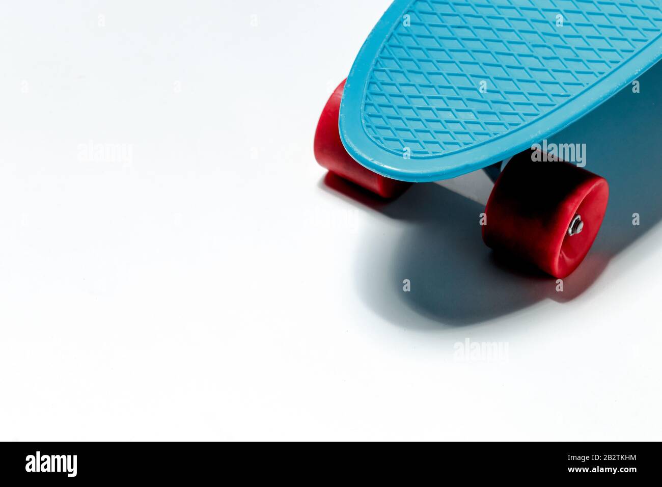 Crociera con skateboard blu con ruote rosse su sfondo bianco e spazio per le copie Foto Stock