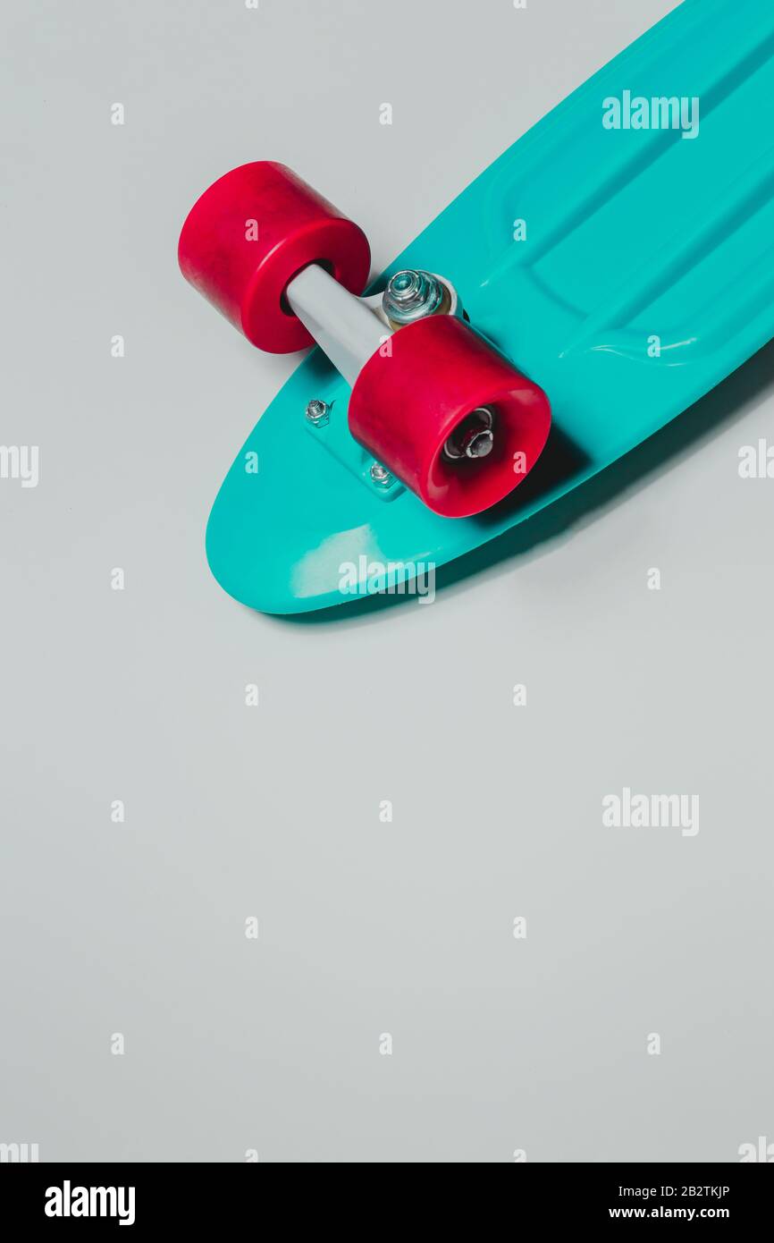 Cruiser da skateboard verde con ruote rosse su sfondo grigio con spazio di copia Foto Stock