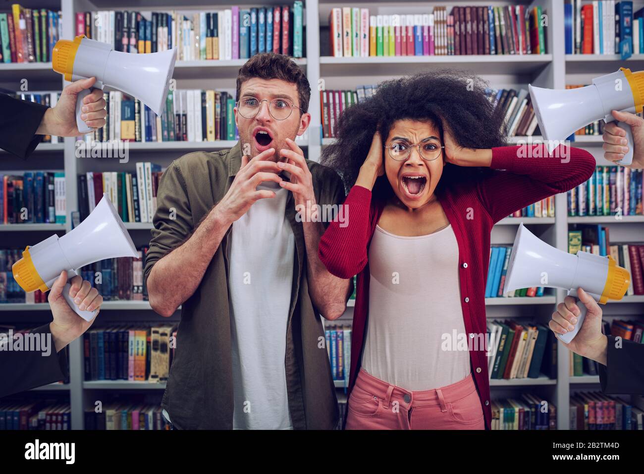 Gli studenti sono preoccupati e infastiditi a causa dell'elevato volume di megafono in una biblioteca Foto Stock