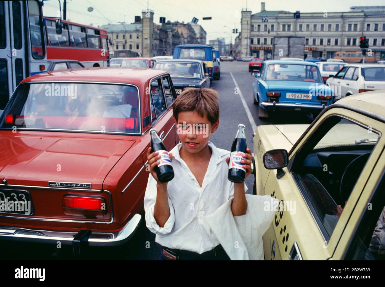 Giovane Roma (Gypsy) ragazzo che vende Pepsi, soft drink, su una trafficata Mosca, RU, strada, vicino al mercato Rizhsky, la sera. 1992. Foto Stock