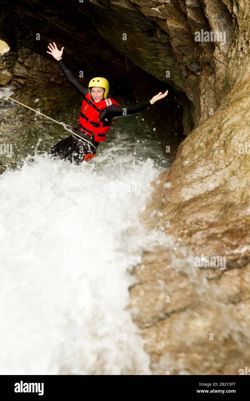 Matura Femmina Indossare Seal Equipment Descending A Waterfall Foto Stock