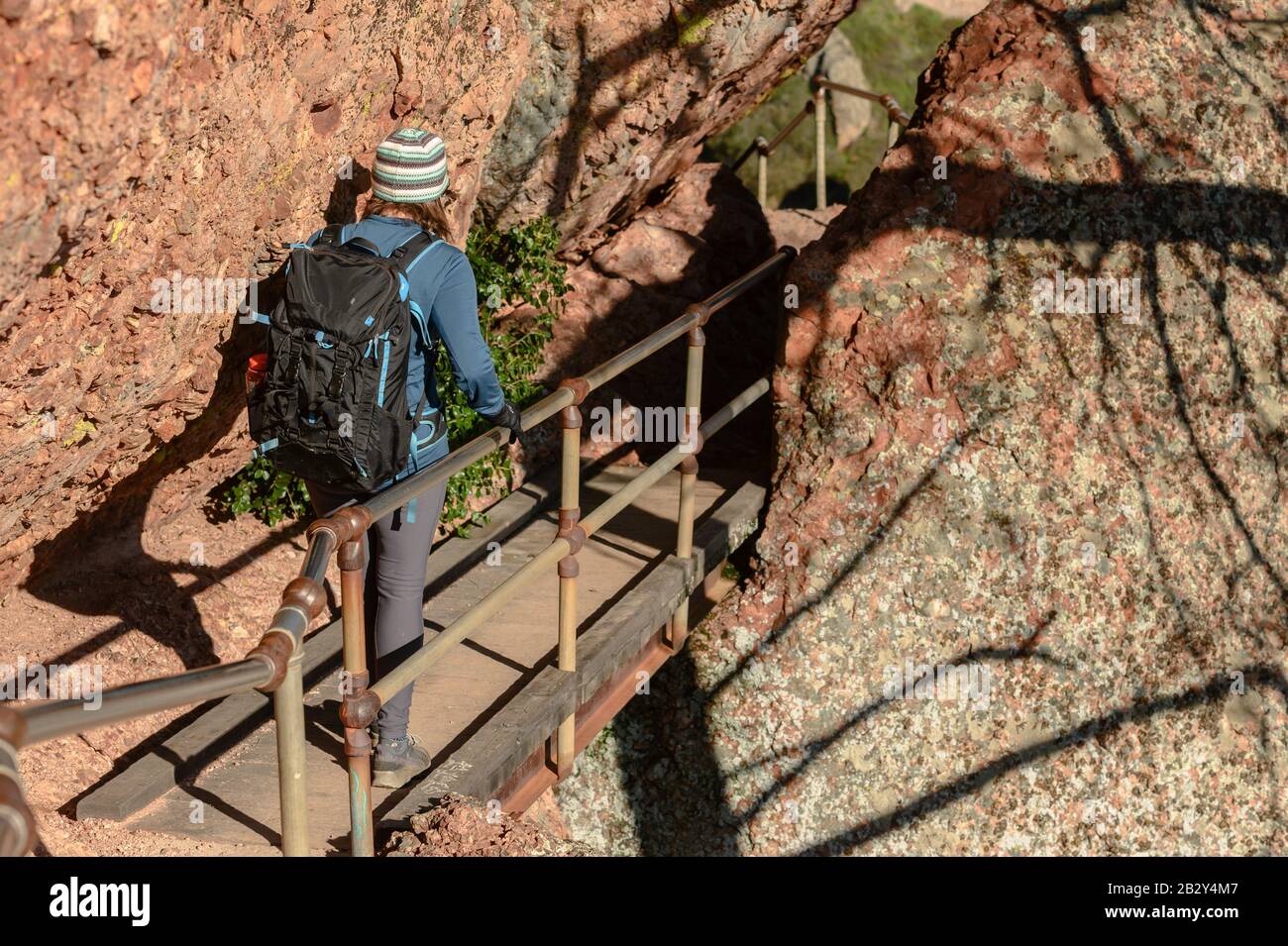 Donna Attraversa il ponte Di Metallo sospeso a lato della scogliera Foto Stock