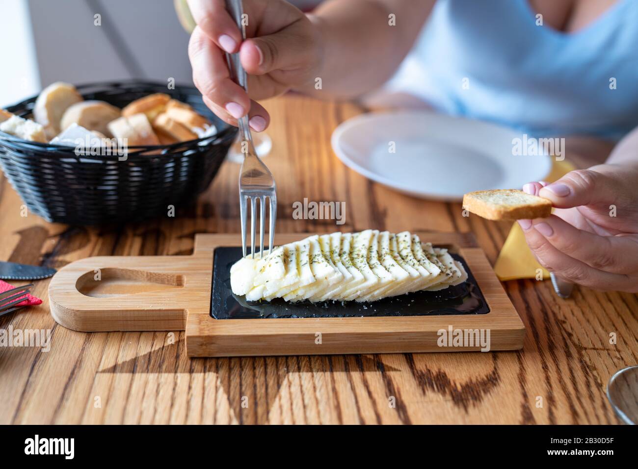Le mani della donna che raccoglie il formaggio con il pane al tavolo del ristorante Foto Stock
