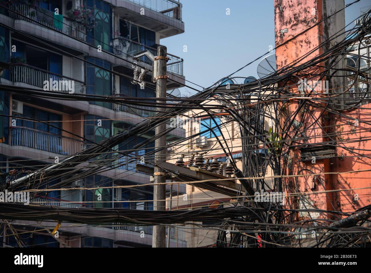 Yangon, Myanmar città Street vista con una massa di cavi elettrici a soffitto che collegano gli abitanti della città alla rete. Foto Stock