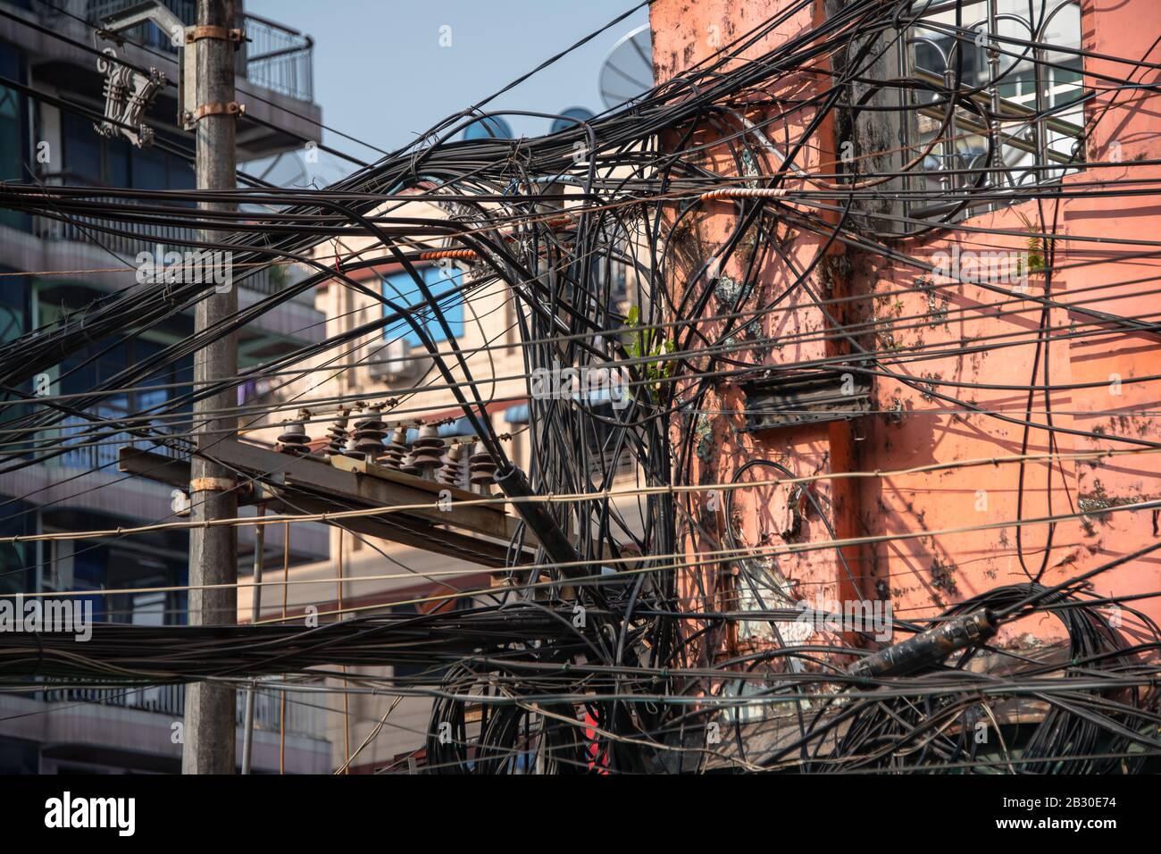 Yangon, Myanmar città Street vista con una massa di cavi elettrici a soffitto che collegano gli abitanti della città alla rete. Foto Stock