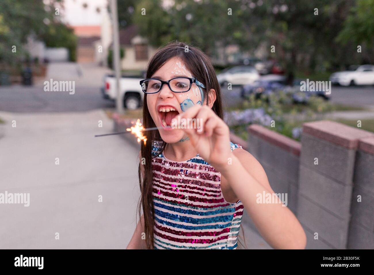 I bambini giocano con i luccisti sul loro vialetto in città sulla 4th di luglio. Foto Stock