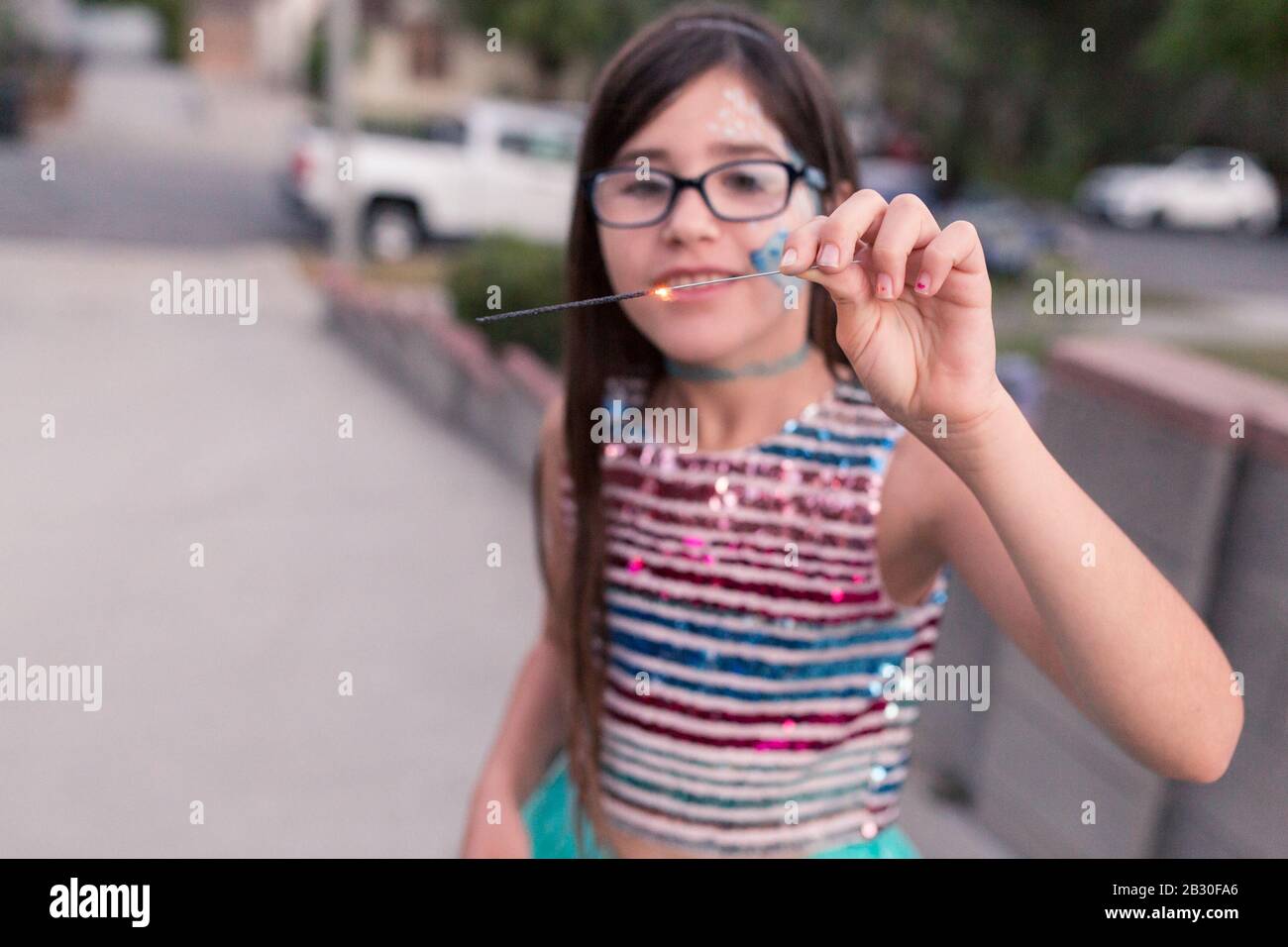 I bambini giocano con i luccisti sul loro vialetto in città sulla 4th di luglio. Foto Stock