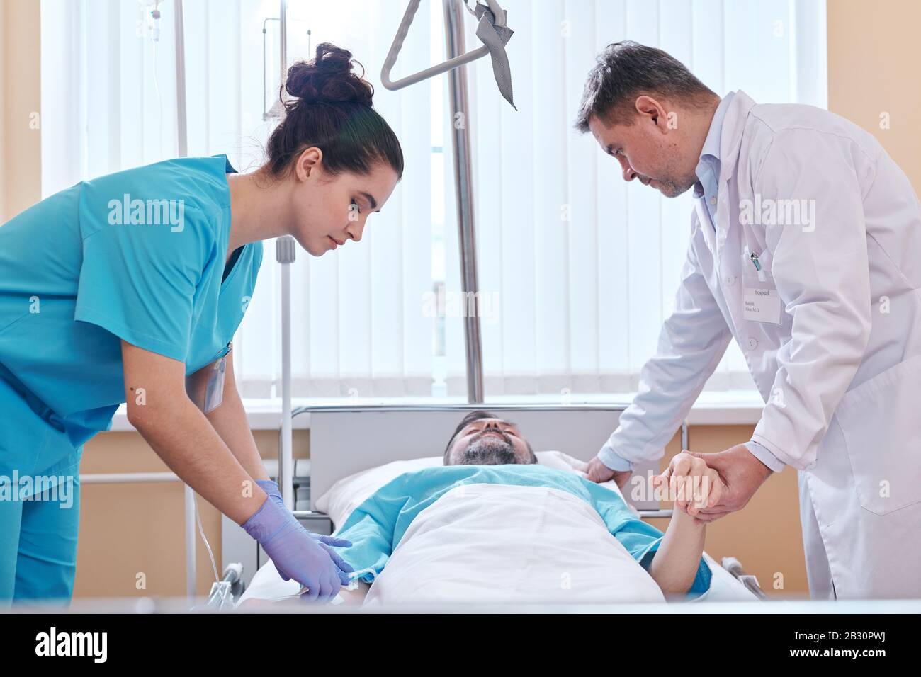 Infermiere e medico in piedi al letto dell'ospedale e controllo delle condizioni del paziente Foto Stock