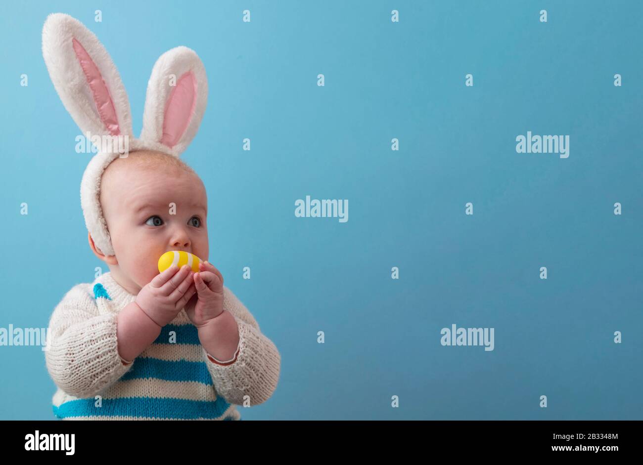 Carino bambino che indossa orecchie di coniglio di pasqua giocare con un uovo di pasqua Foto Stock