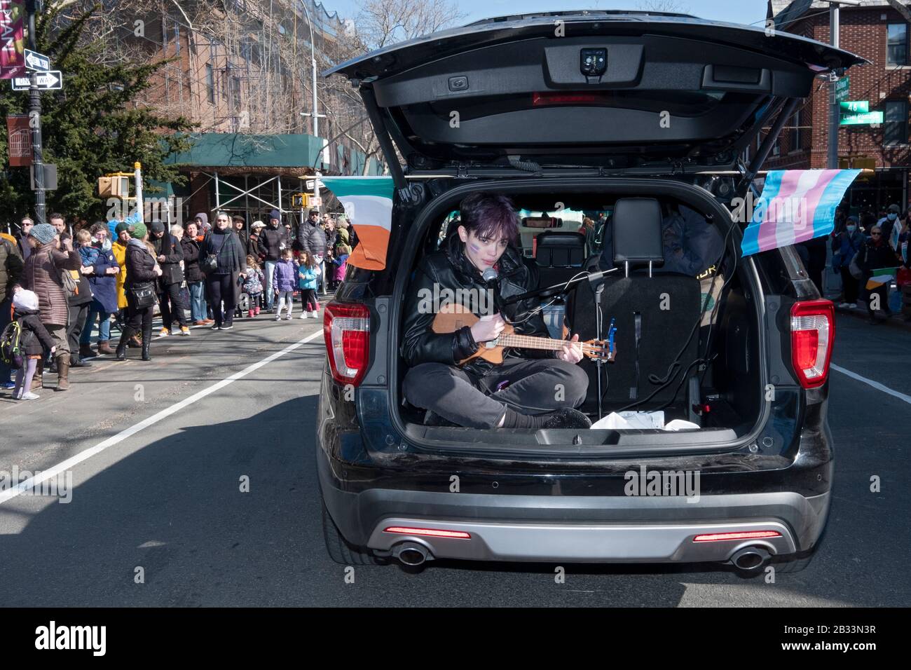 Vicino alla conclusione del giorno di San Patrizio per Tutta la parata, un giovane suona una chitarra nella parte posteriore di un carro della stazione. A Sunnyside, Queens, New York. Foto Stock