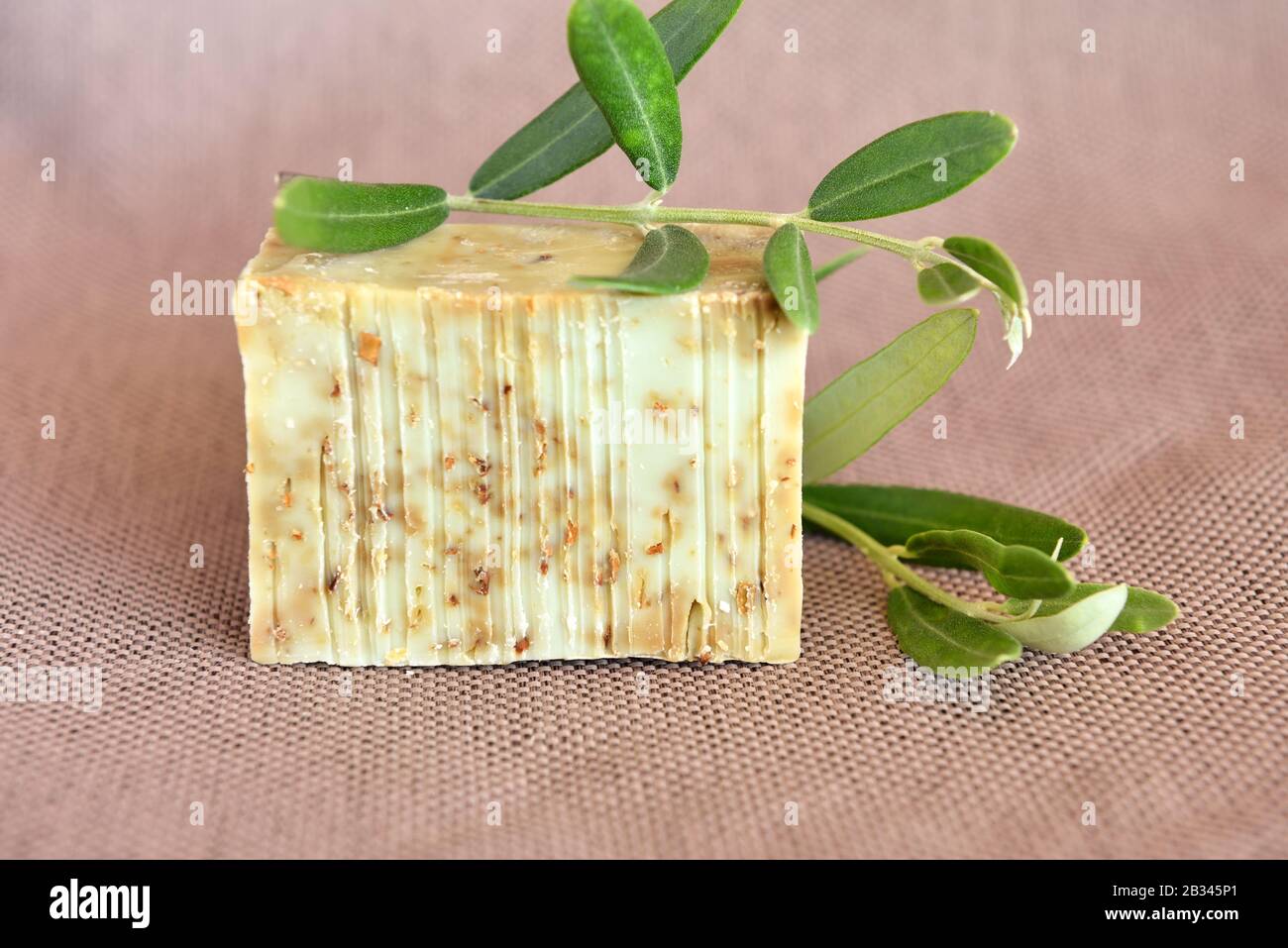 Saponette fatte a mano e rami d'oliva su sfondo gunny Foto Stock