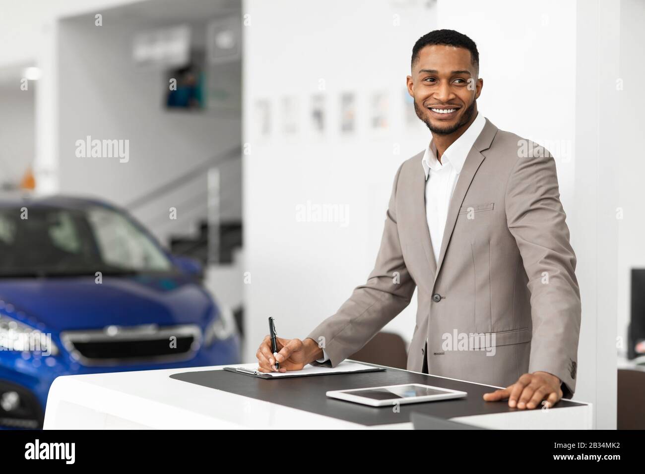 Venditore Di Auto Uomo In Piedi Presso Il Banco Di Lavoro Presso L'Ufficio Della Concessionaria Foto Stock