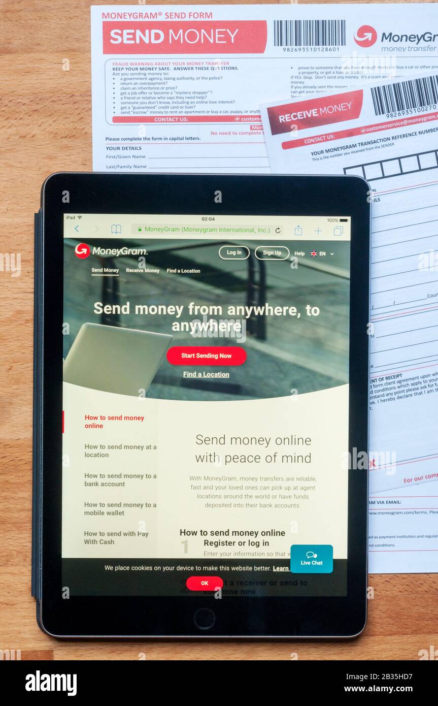 Il sito di trasferimento di denaro moneygram visualizzato su un tablet ipad insieme a moduli stampati per l'invio e la ricezione di denaro. Foto Stock