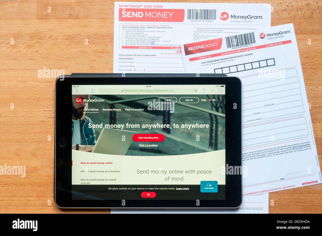 Il sito di trasferimento di denaro moneygram visualizzato su un tablet ipad insieme a moduli stampati per l'invio e la ricezione di denaro. Foto Stock