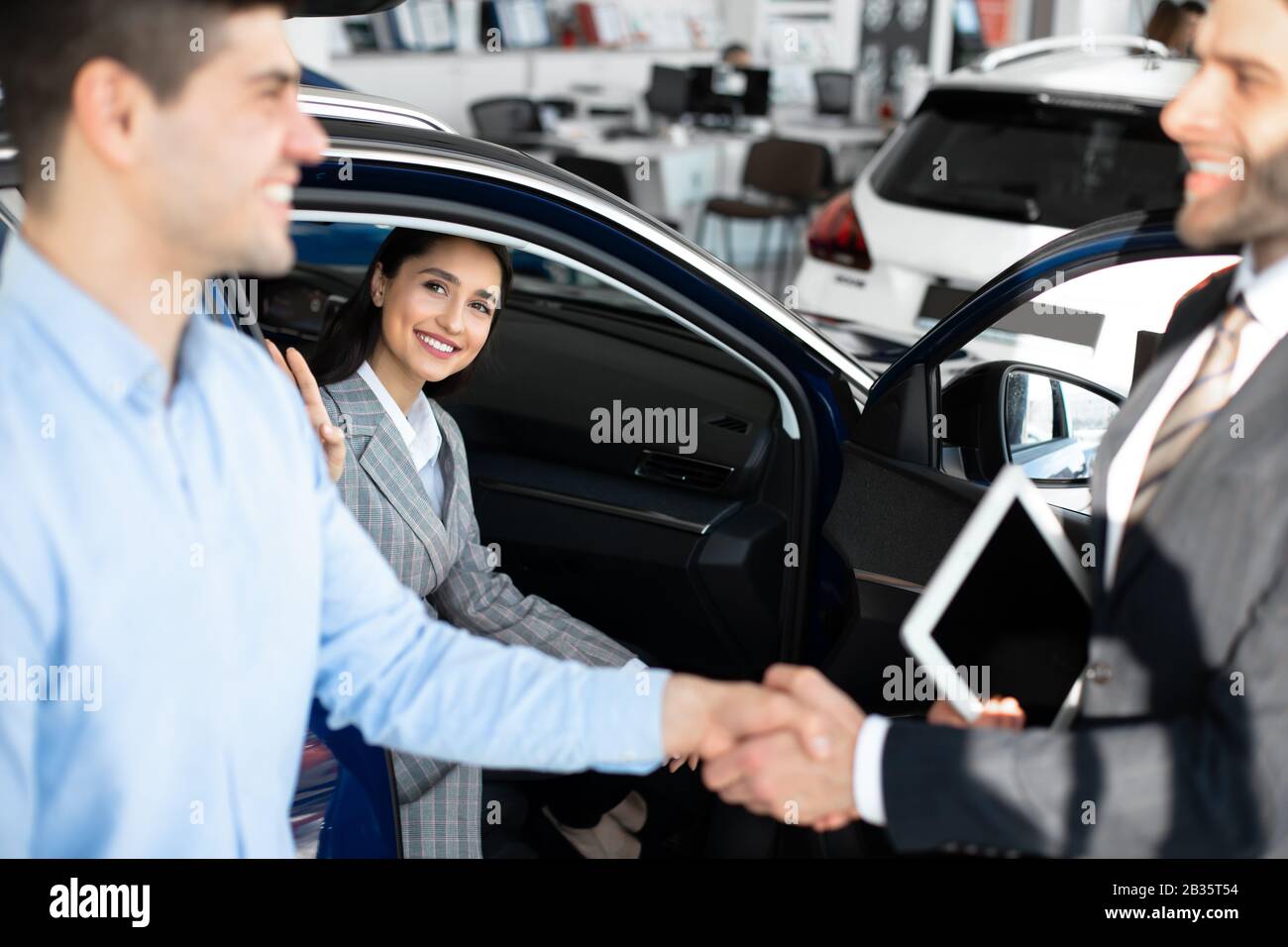 Uomo Che Si Stringe Le Mani Con Il Responsabile Delle Vendite Di Auto Nel Dealership Store Foto Stock