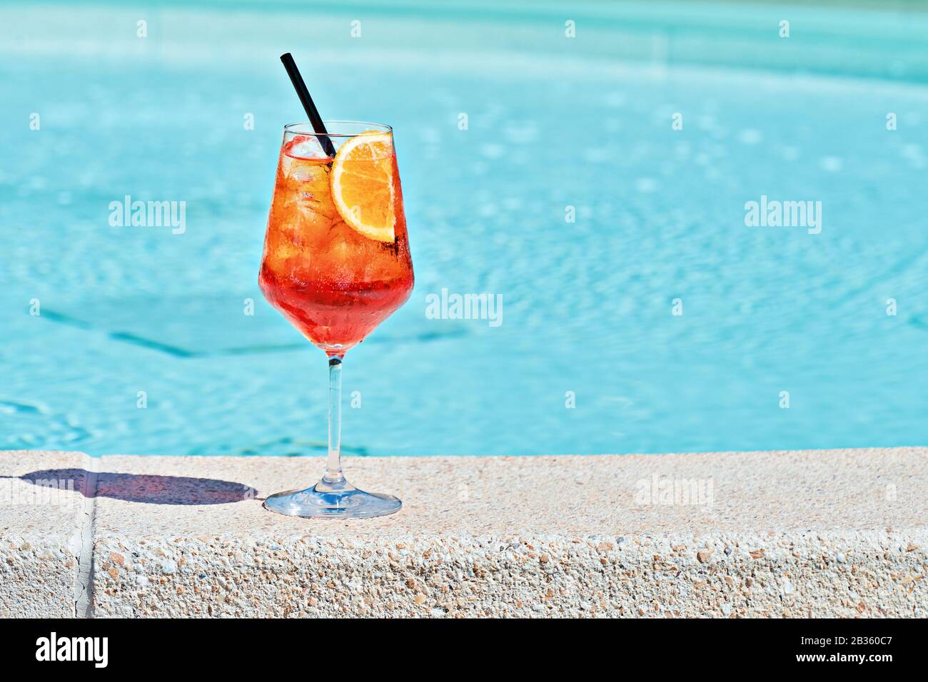 Vino bicchiere di cocktail freddo Aperol spritz contro acque turchesi della piscina. Tradizionale aperitivo estivo italiano concetto cocktail Foto Stock