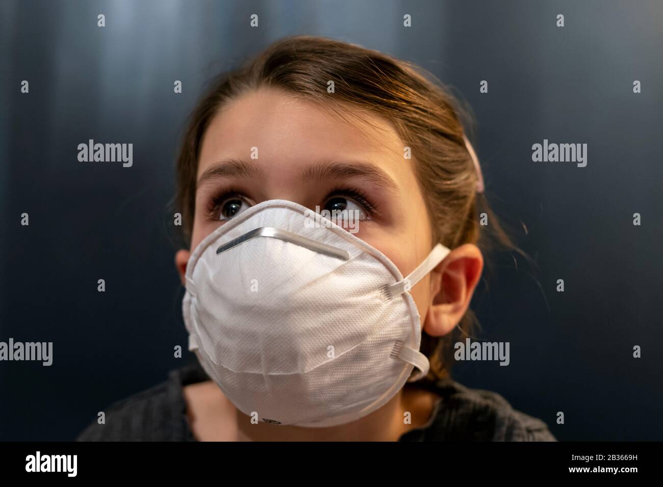 Giovane ragazza che indossa una maschera di protezione contro il virus corona Foto Stock