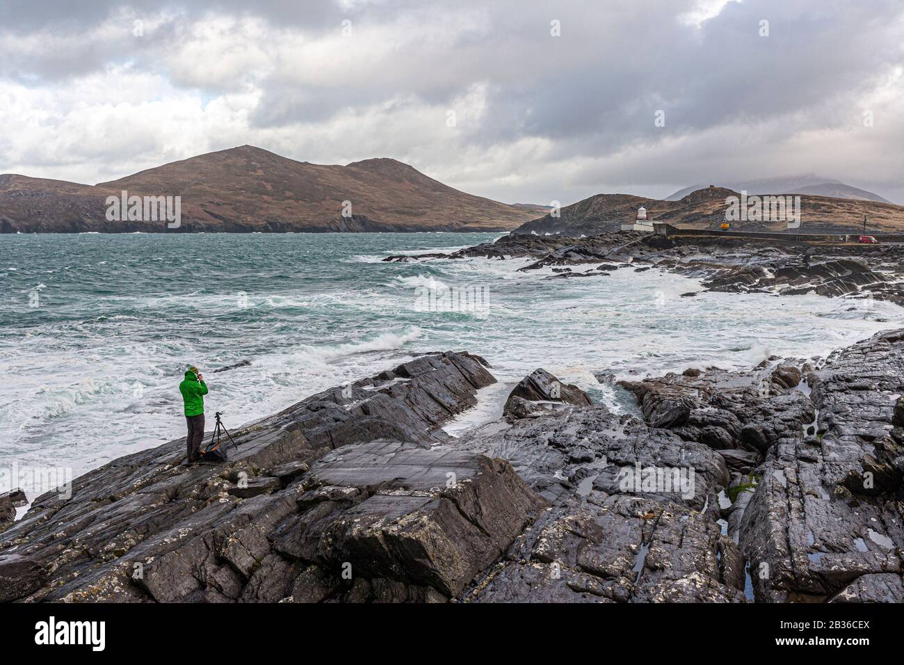 Fotografo sulle rocce durante la tempesta fotografando il faro dell'isola di Valentia, County Kerry, Irlanda Foto Stock