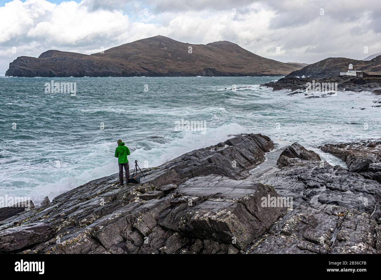 Fotografo sulle rocce durante la tempesta fotografando il faro dell'isola di Valentia, County Kerry, Irlanda Foto Stock