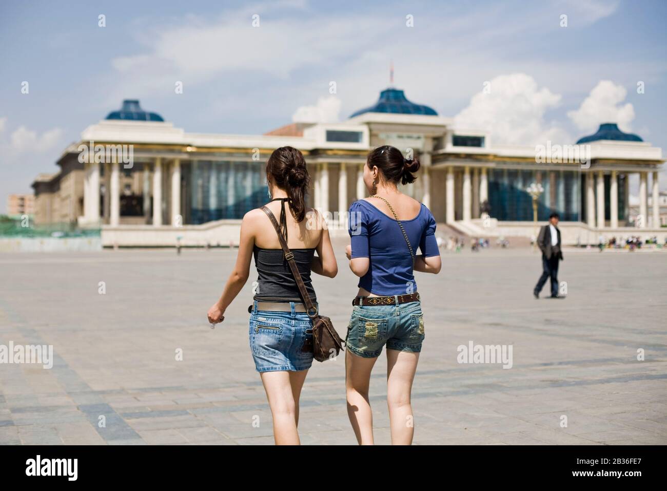 Mongolia, Ulan Bator, due giovani donne mongolo visto da dietro a piedi verso il Palazzo del Governo su Chingis Khaan Square, precedentemente noto come Piazza Sukhbaatar Foto Stock