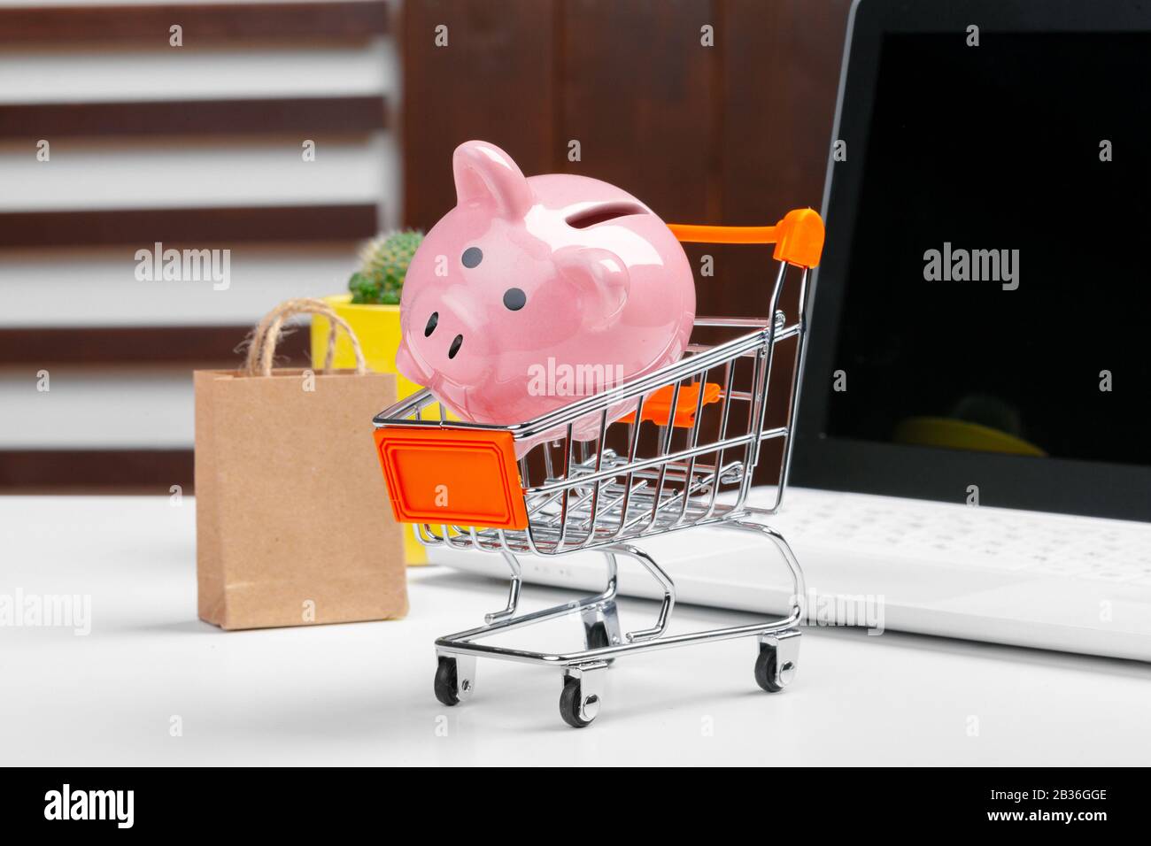 Shopping online concetto. Carrello spesa, laptop sulla scrivania Foto Stock