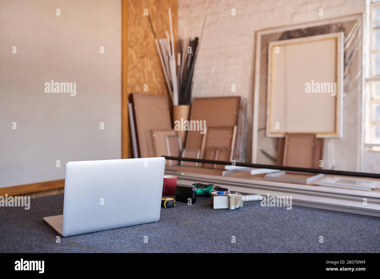 Taglierina per tappeti e computer portatile su un tavolo da officina per incorniciatura di immagini Foto Stock