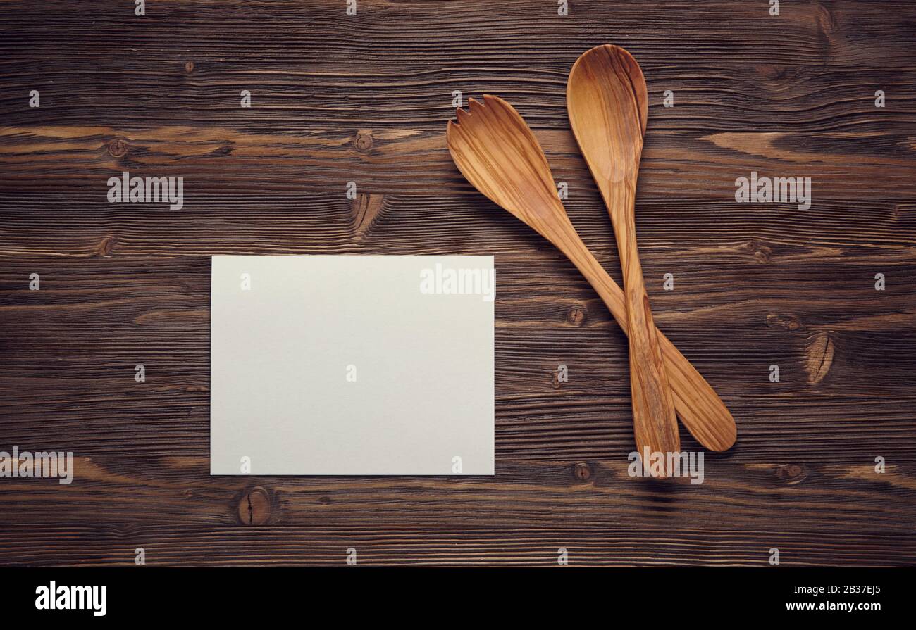 Chiudete i cucchiai di legno e la carta bianca su una tavola di legno. Vista dall'alto. Foto Stock